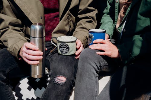 Voluminous marching thermos for hot tea or coffee stands on ground